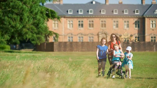 Visitors exploring parkland with Tredegar House, Newport in background